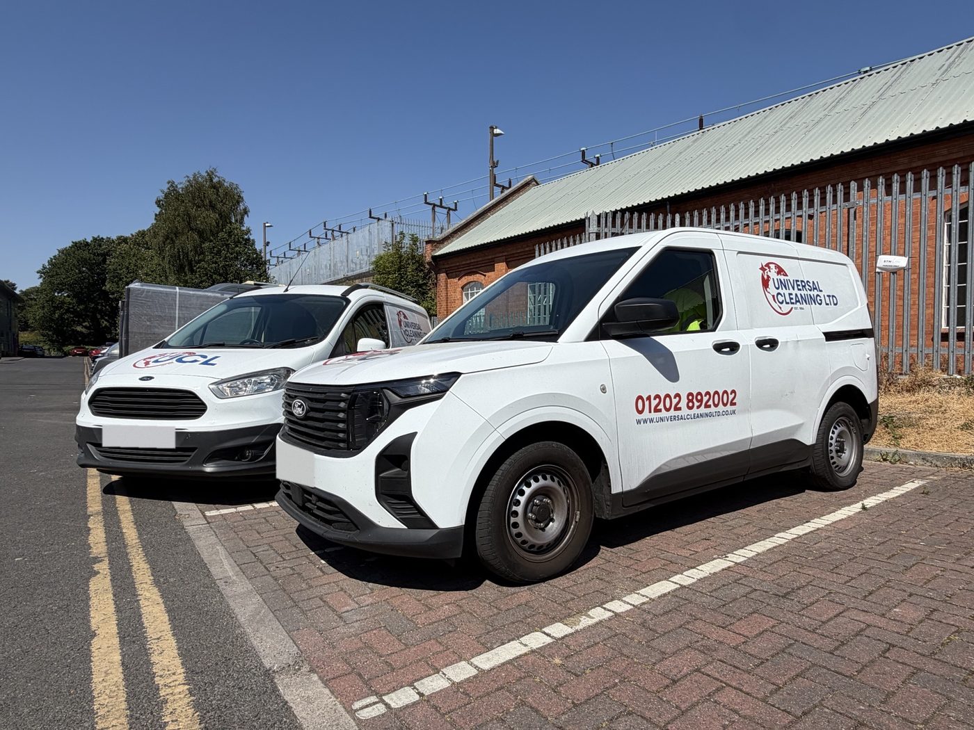 Two Universal Cleaning Ltd vans in the red and blue UCL livery, parked outside the unit