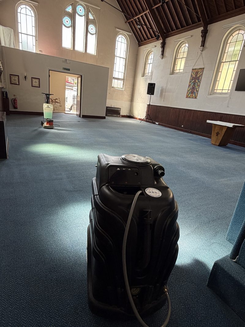 A carpet extractor and a floor machine part-way through cleaning a community hall
